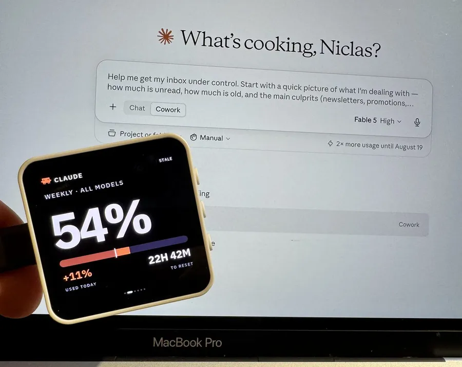 Niclas holding the square VibePulse display in front of a laptop, showing Claude usage